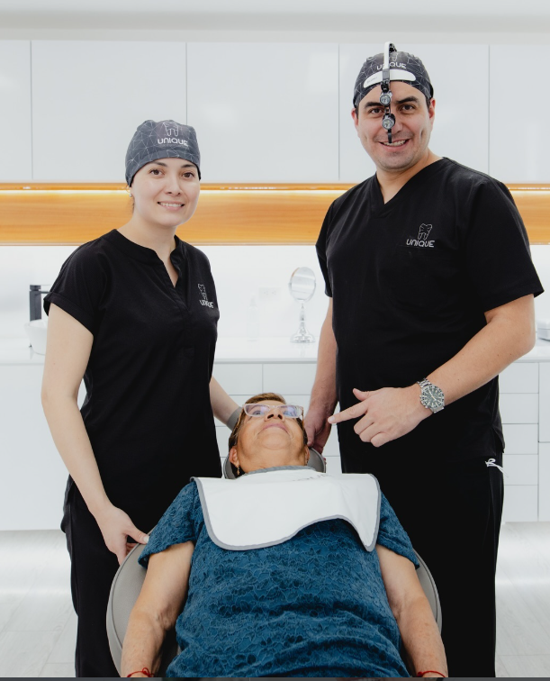 Dr. Paul junto a su equipo, preparando a una paciente para su procedimiento de implantes